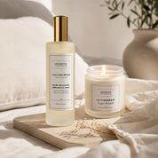 Duo du flacon de la brume relaxante L'Eau des Rêves à la verveine citronnée et de la bougie végétale La Figueraie Hendiya, posés ensemble sur un plateau avec du linge, pour une ambiance relaxante à la maison.